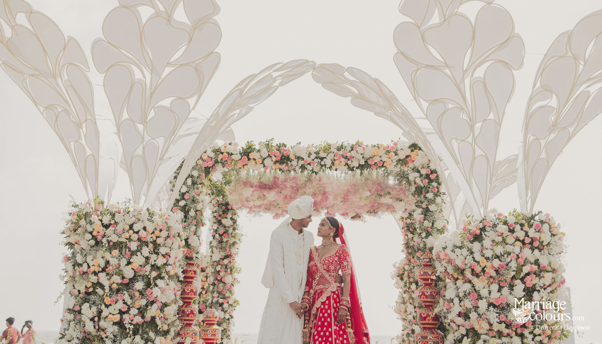 Destination wedding couple standing under a decorated floral mandap at a luxury Indian beach wedding in Mahabalipuram.