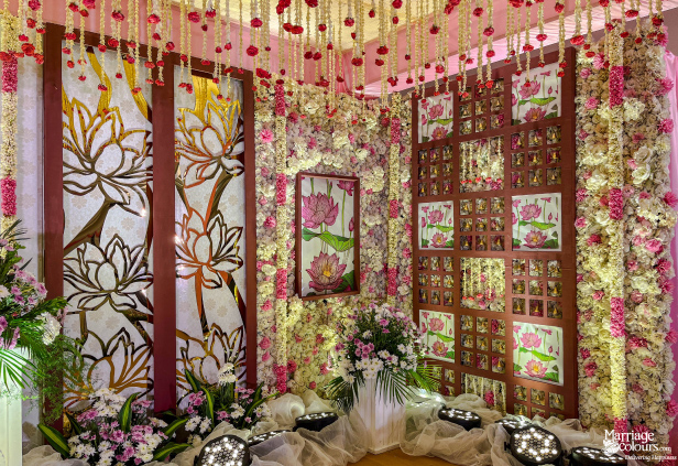Intimate wedding decor corner with gold lotus panels, a floral wall, and hanging pink and white flowers.