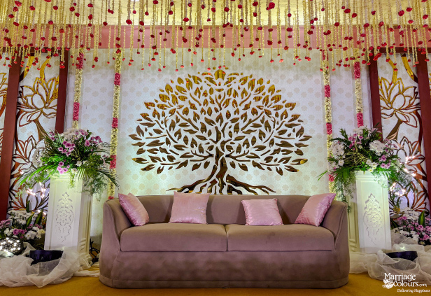 Romantic stage with a golden Tree of Life backdrop, pink velvet sofa, and hanging flower strings.