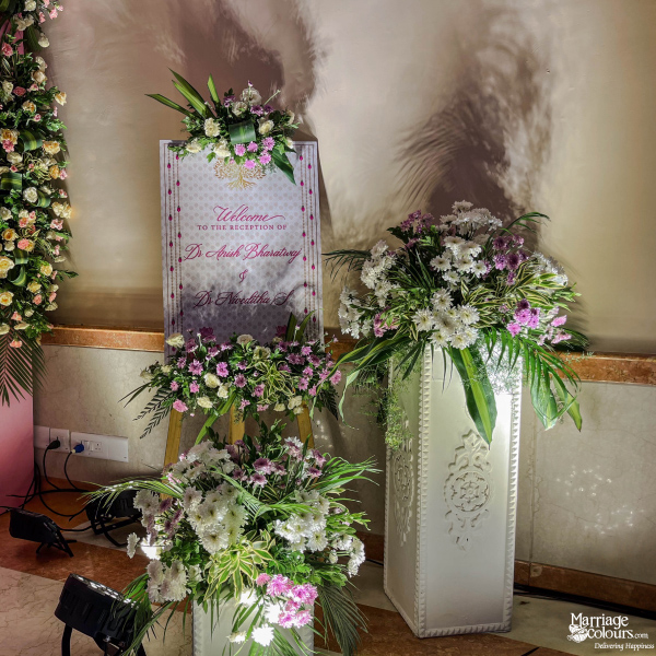 Welcome sign for Dr. Anish Bharadwaj and Dr. Niveditha S, surrounded by lush white and purple flowers.