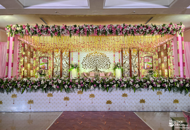 Elaborate pink and white floral wedding stage with a prominent golden Tree of Life backdrop.
