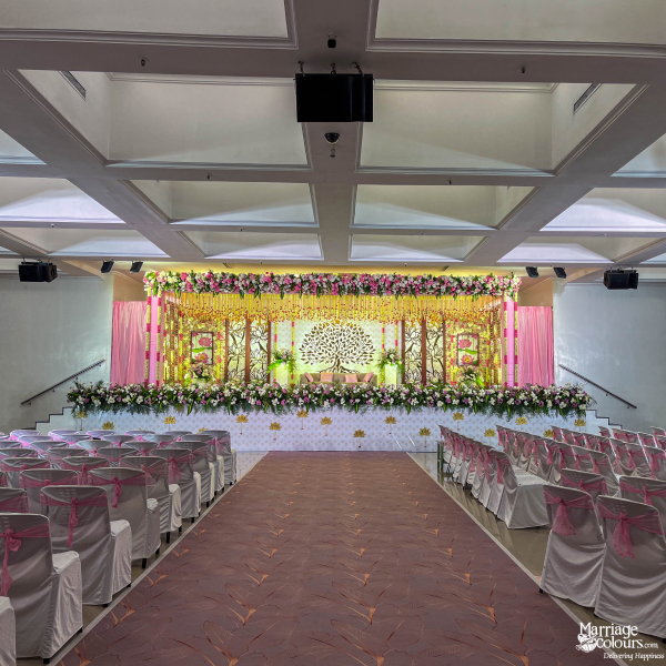 Wedding hall with white chairs, pink sashes, and a romantic Tree of Life stage backdrop.