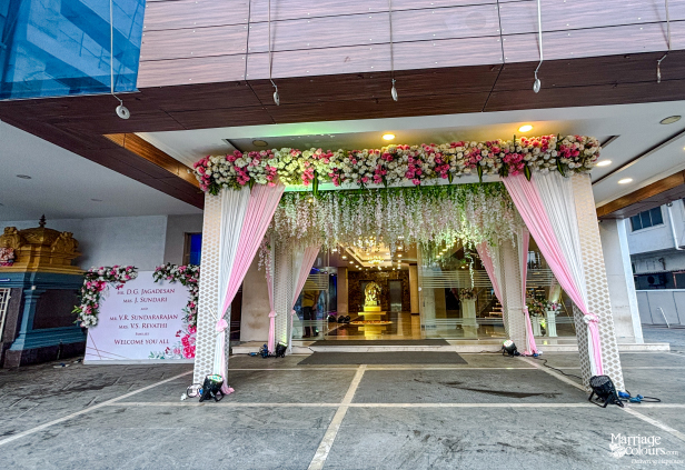 Building entrance decorated with pink and white draping, roses, and a welcome sign.