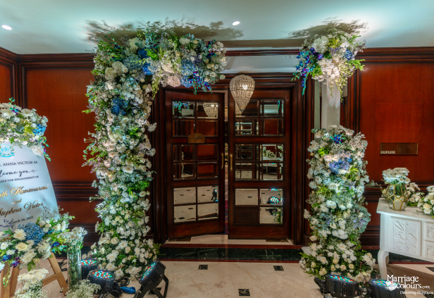 Grand hotel entrance decorated with a lush floral archway of white, blue, and green flowers.