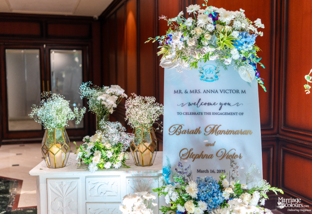 Close-up of a frosted welcome sign for an engagement, decorated with blue, white, and green florals.