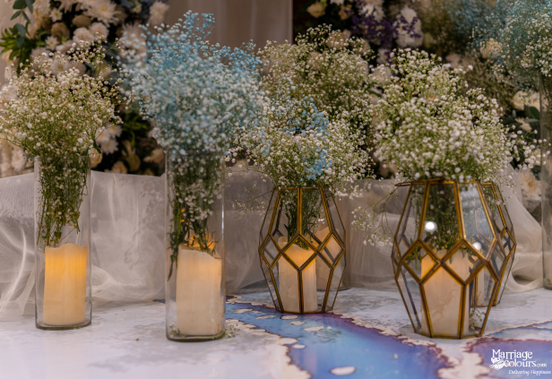 Wedding floor decor showing baby's breath flowers, glowing candles, and modern brass terrariums.