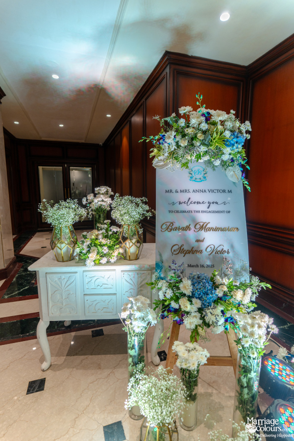 Elegant welcome sign for an engagement celebration, adorned with lush blue and white floral arrangements.