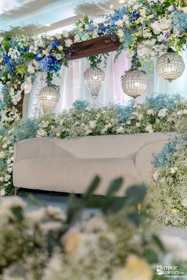 Elegant wedding stage with white-blue flowers, lantern lights, and plush sofa