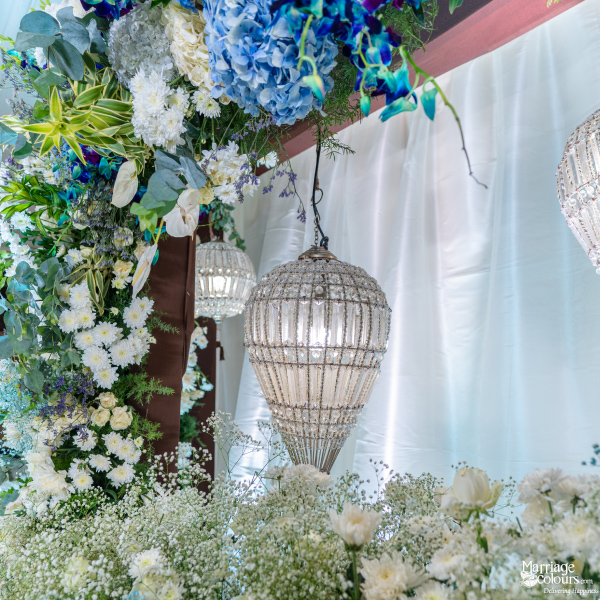 Floral wedding decor with chandeliers, white drapes, and blue-white flowers