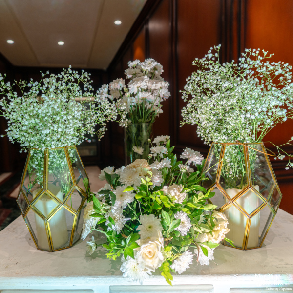 Wedding decor featuring geometric terrariums with baby's breath and a cluster of white roses and mums.
