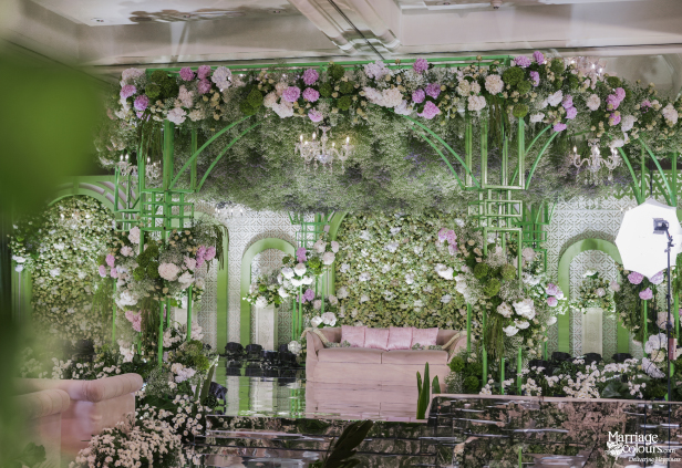 Highly detailed view of a luxurious wedding stage featuring a floral wall and green geometric framework.