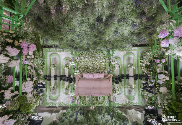 Close-up, overhead view of an elaborate wedding stage covered in flowers, greenery, and reflections.