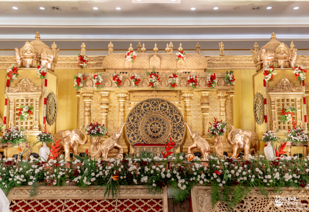 Spectacular, wide-view of an ornate South Indian wedding stage heavily decorated with gold carvings.