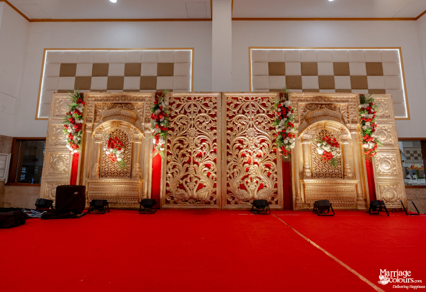 Traditional Hindu wedding stage featuring intricate gold carvings, red backdrop, and a red-carpet floor.