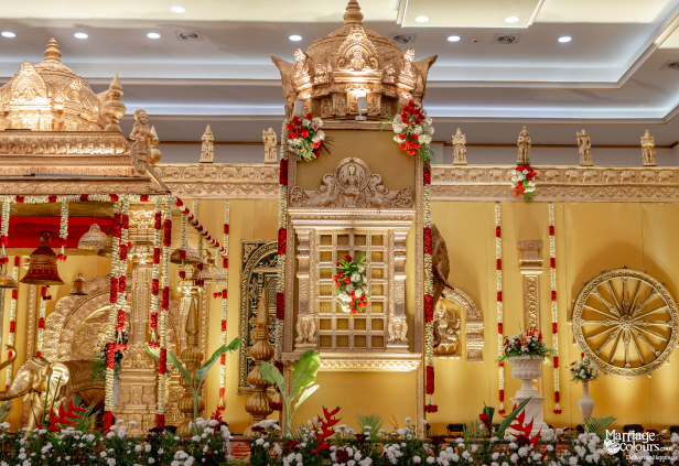 Close-up of an ornate South Indian wedding stage centerpiece with extensive gold and floral decorations.