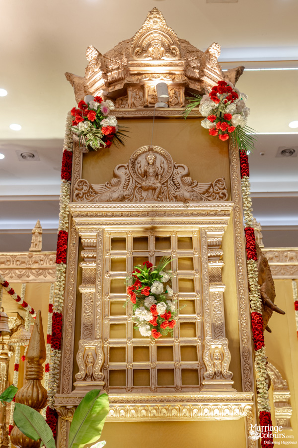 Vertical view of a traditional, towering South Indian wedding decor pillar with intricate gold carvings.