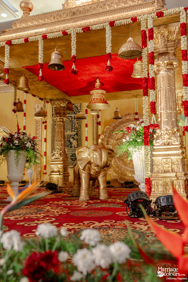 Close-up of a richly decorated Hindu wedding mandap featuring gold pillars and a central elephant statue.