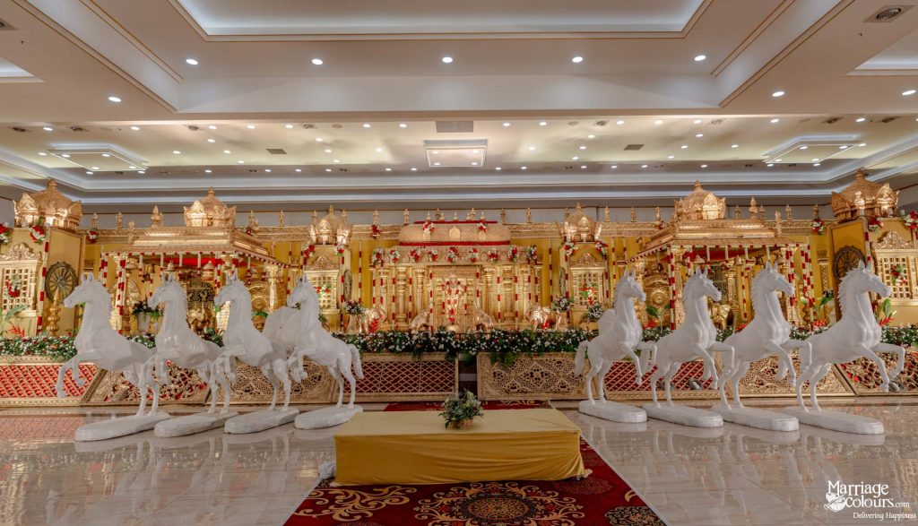 Grand wedding stage featuring traditional gold architecture and a striking line of white horse statues.