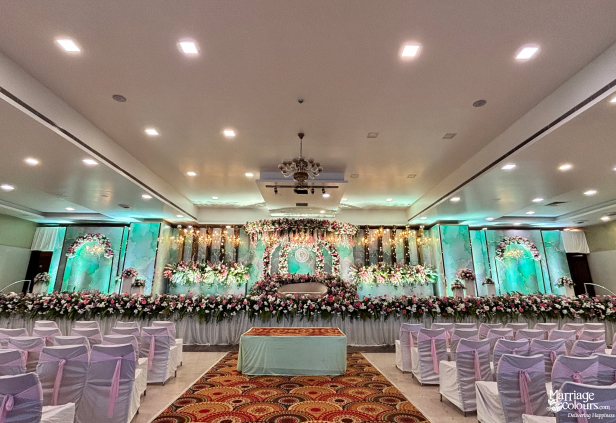 Wide view of grand hall with pink chairs facing a modern floral stage.