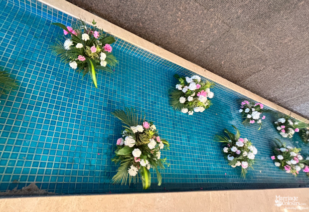 Teal mosaic tiled pool with bouquets of white and pink flowers floating on the water.