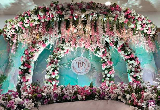 Modern stage backdrop with teal marble pattern, floral archway, and 'PD' monogram.