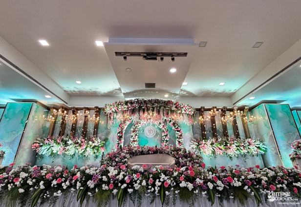 Modern stage with teal backdrop, white couch, and full border of pink and white flowers.