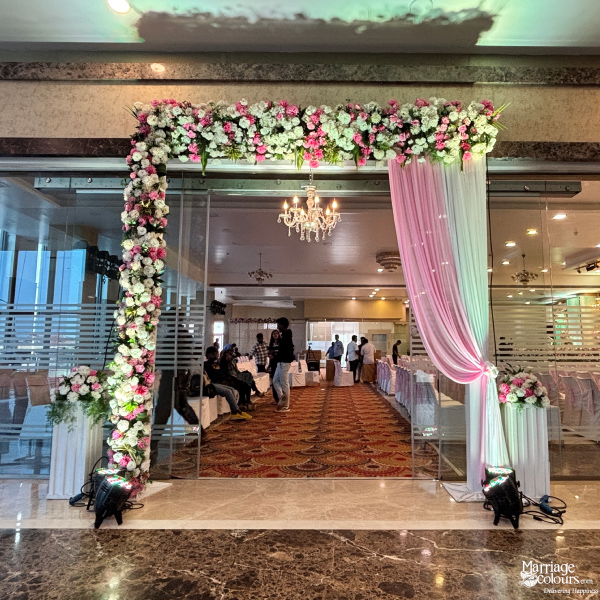 Indoor venue entrance with pink and white drapes and a garland of mixed flowers.