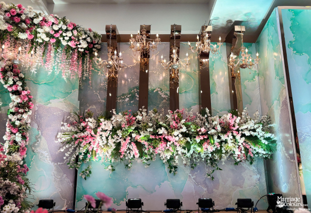 Modern stage backdrop with teal marble pattern, mirror panels, and large floral arrangement.