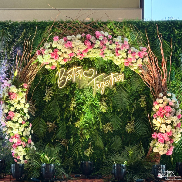 Green floral wall backdrop with neon sign "Better Together" and rustic branches.