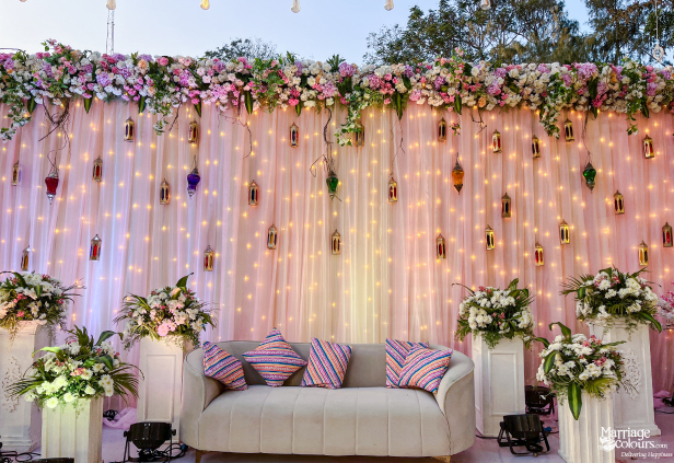 The central wedding stage featuring a gray loveseat, floral top border, and sparkling peach drapes.