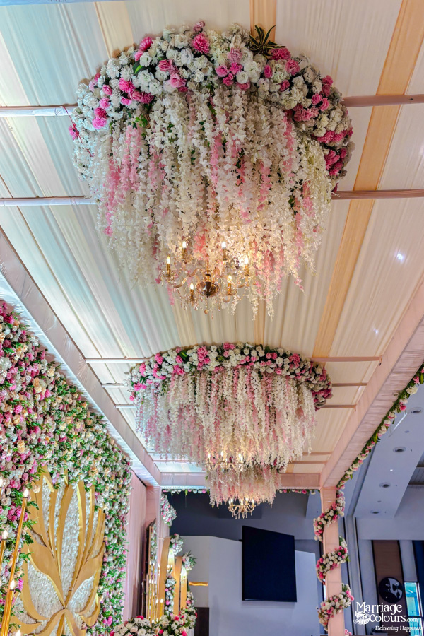 Stunning overhead floral chandeliers with cascading pink and white wisteria under a draped ceiling.