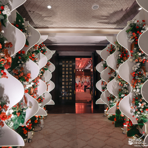 Decorative event hallway with wavy white floral walls leading to a distant brightly lit room.