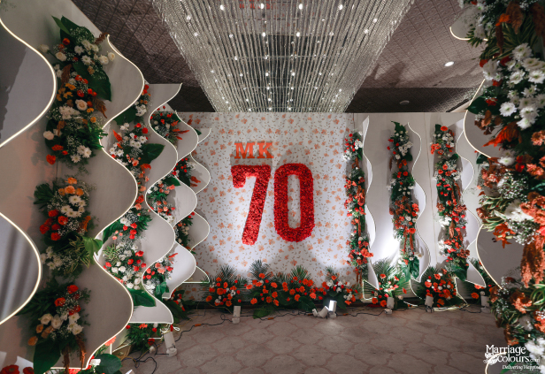 Celebration stage backdrop with a large red floral '70' and white wavy columns.