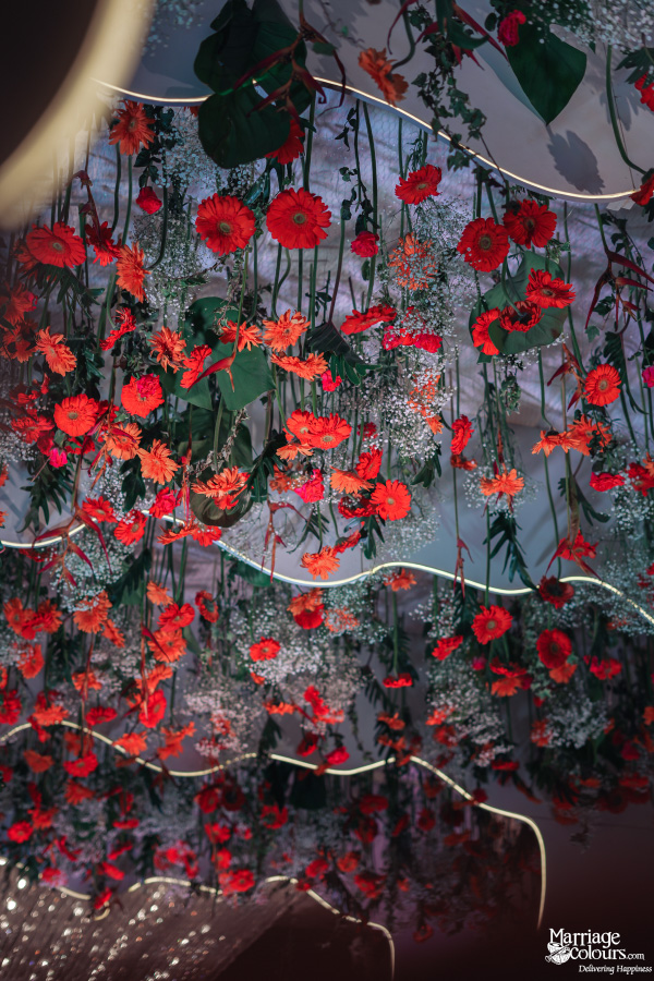 Vibrant red and orange flowers hanging from a decorated ceiling.