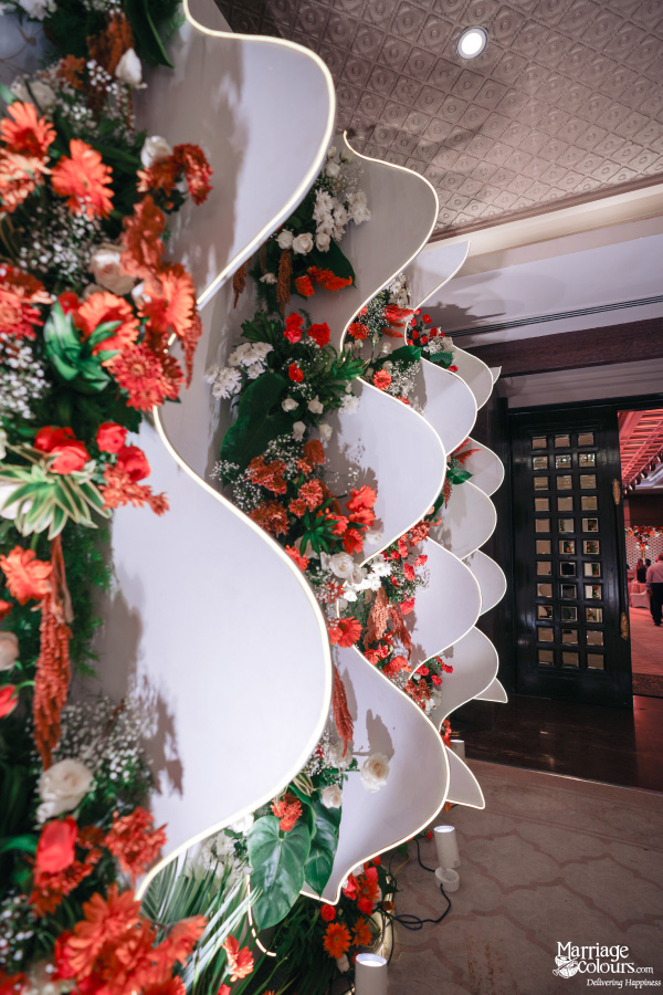 Intricate floral display on wavy white panels at an event venue entrance.