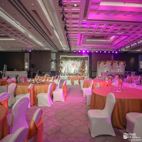 Wide view of an elegant banquet hall set for an event with pink lighting and table arrangements.
