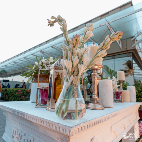 White tuberose flowers in a glass vase on a decorative table with lanterns and candles.