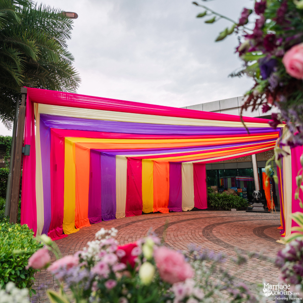 A vibrant entryway tunnel created with horizontal stripes of colorful pink, yellow, and orange fabric.