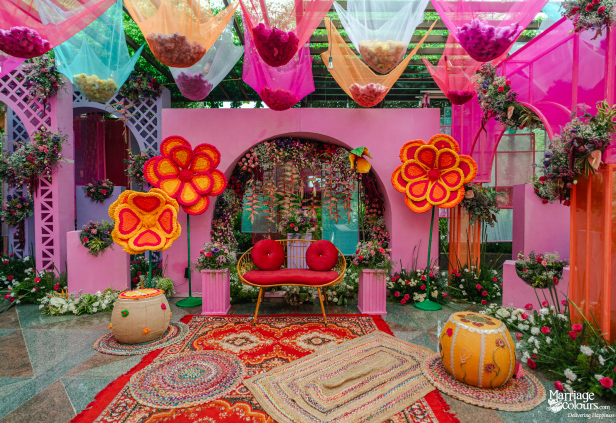 A stunning pink event backdrop featuring large floral cutouts, an archway, and overhead colorful fabric decor