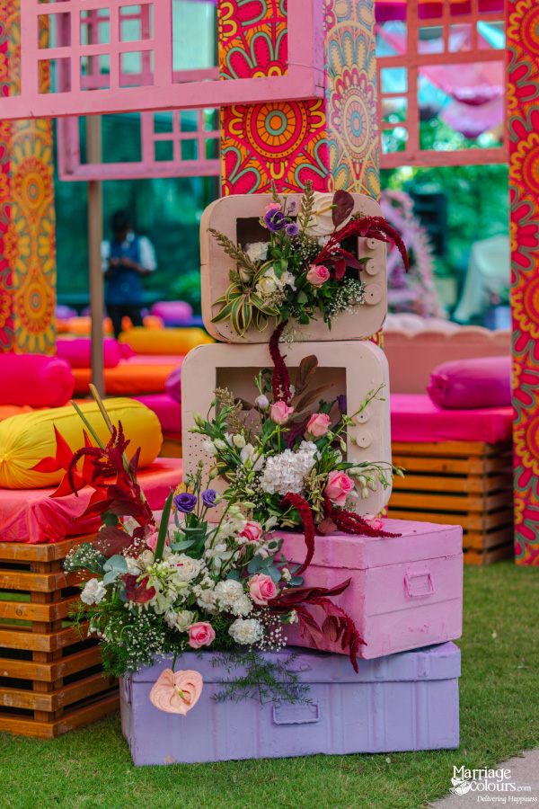 Stacked vintage television sets and suitcases in pastel colors used as a unique floral arrangement display.