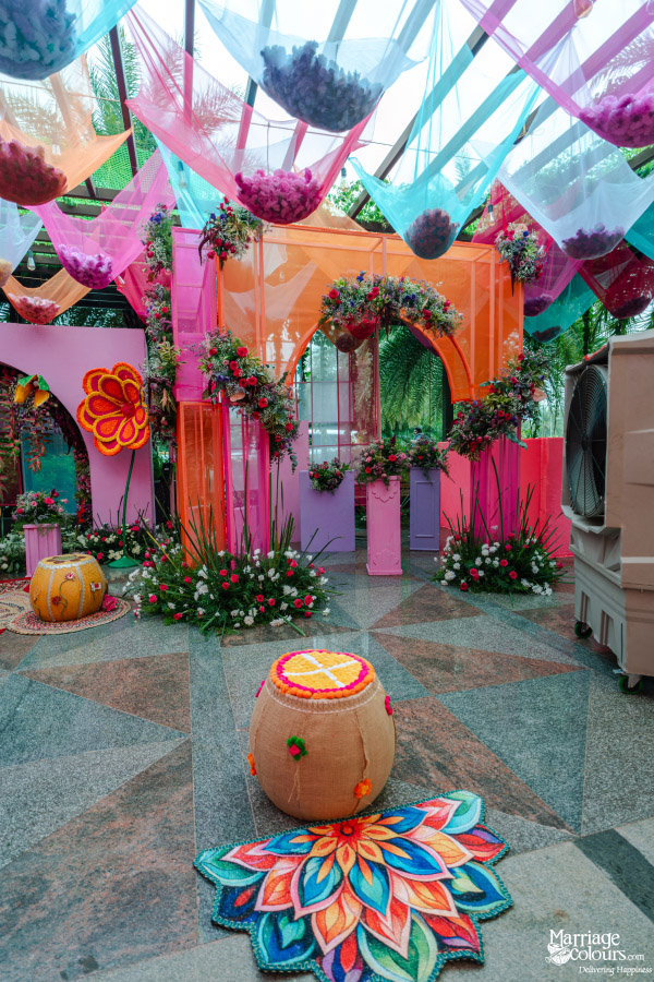 A vibrant, colorful event entrance with pink and orange archways and sheer fabric ceiling decor.