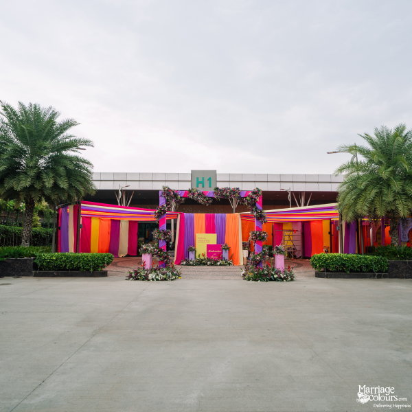 A vibrant event entrance to a venue, framed by colorful striped fabric and floral archways.