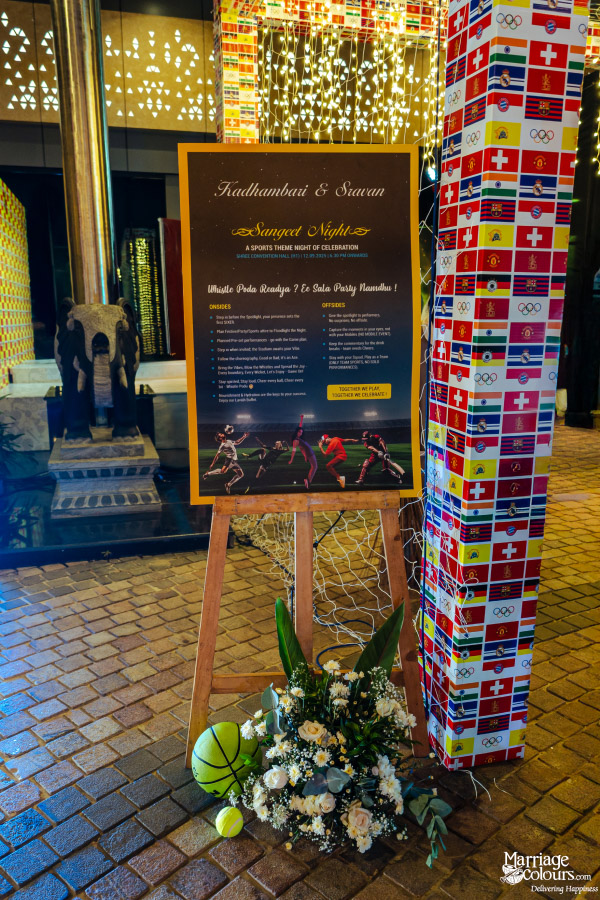 A large, lit Sangeet event sign on an easel, announcing the "Sports Theme Night of Celebration."