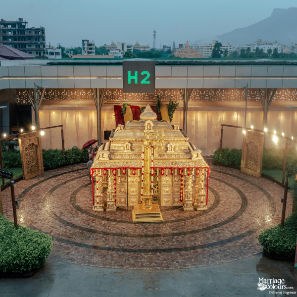 A magnificent golden temple-style structure surrounded by an illuminated brick courtyard and lush greenery at dusk.
