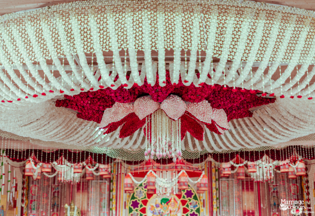 A stunning floral canopy crafted from white and red flower strings, forming a tiered, lotus-like design overhead
