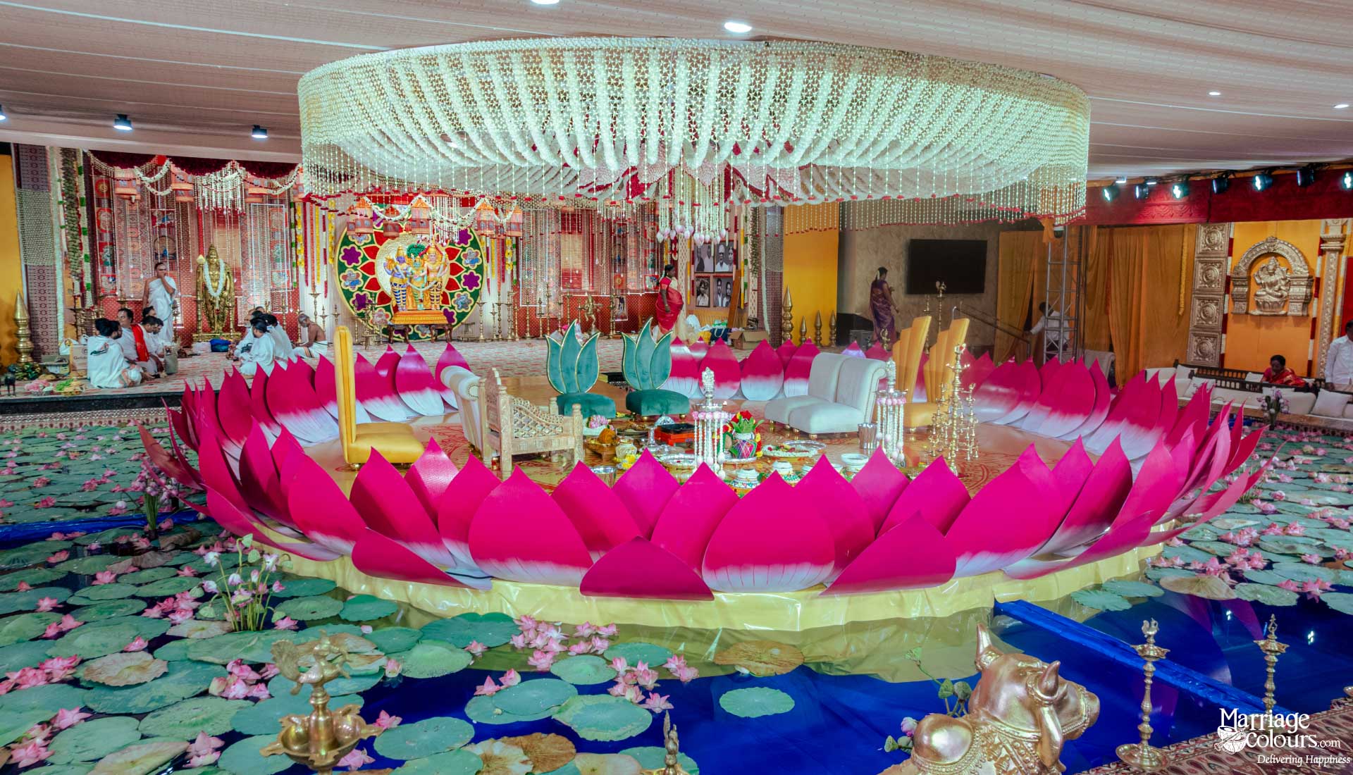 A massive, beautiful pink and white lotus-themed wedding mandap area set over a faux pond.