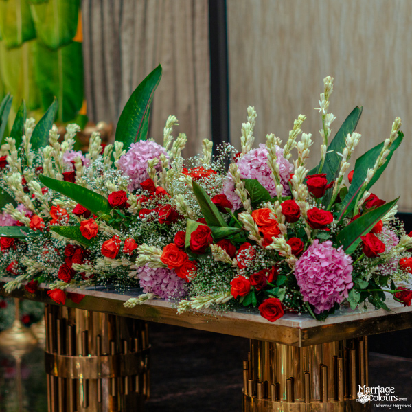 A close-up of a lavish arrangement of pink hydrangeas, red roses, and tall white tuberoses.