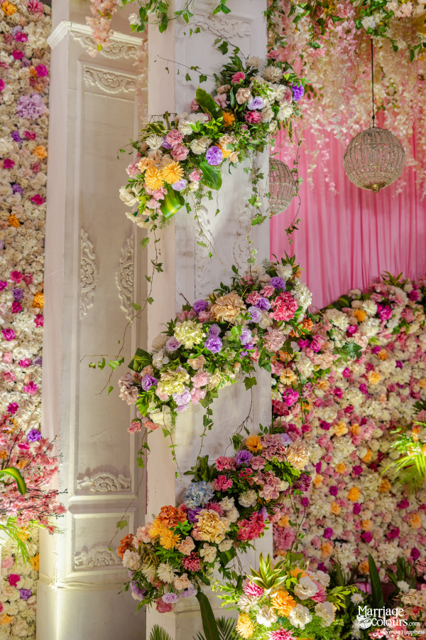 Close-up of a white pillar decorated with cascades of colorful pink, yellow, and purple flowers.