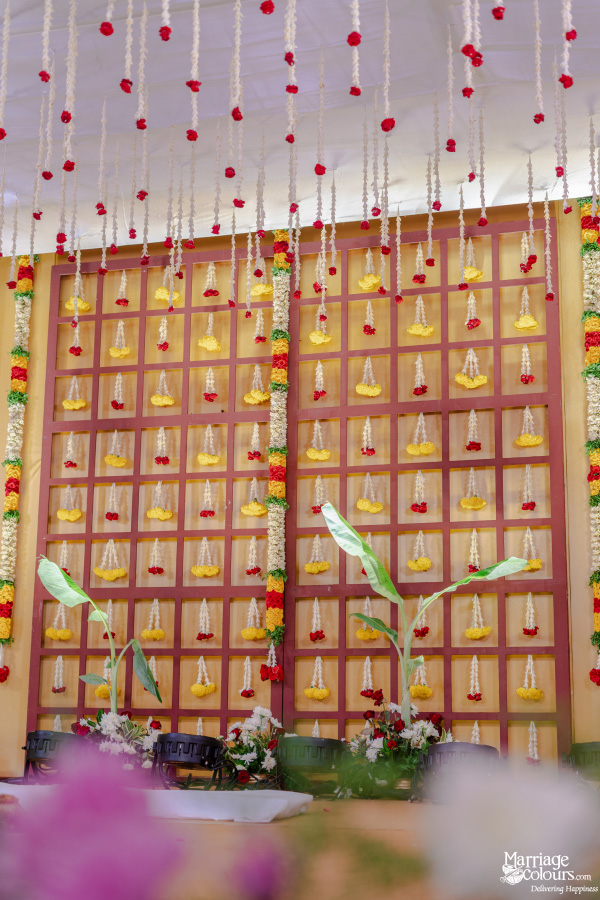 Traditional South Indian stage backdrop with a lattice pattern of yellow and red flower garlands.