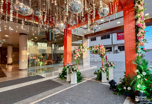 Wedding venue entrance decorated with floral pillars, disco balls, and hanging silver streamers.